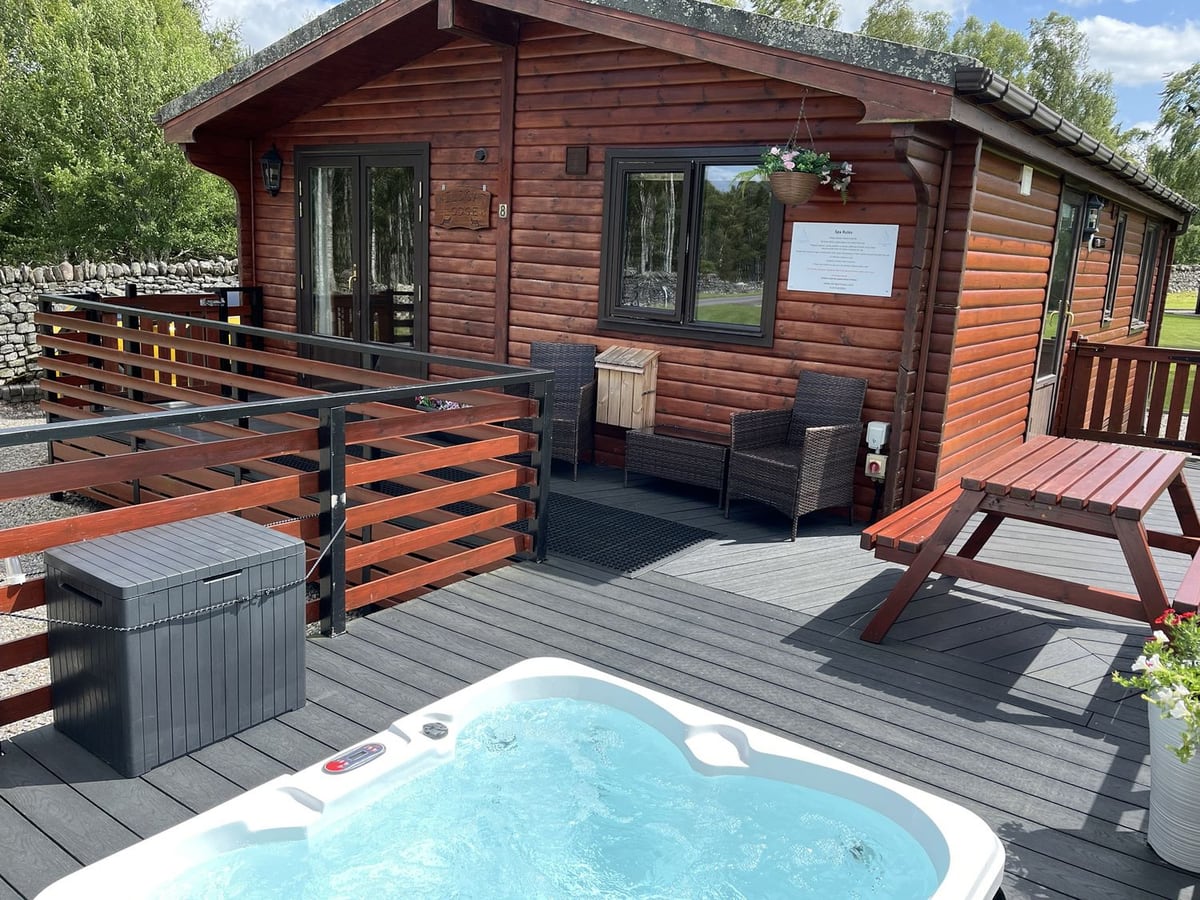 Wildcat Lodge timber cabin with outdoor chairs, a picnic table and hot tub on the deck