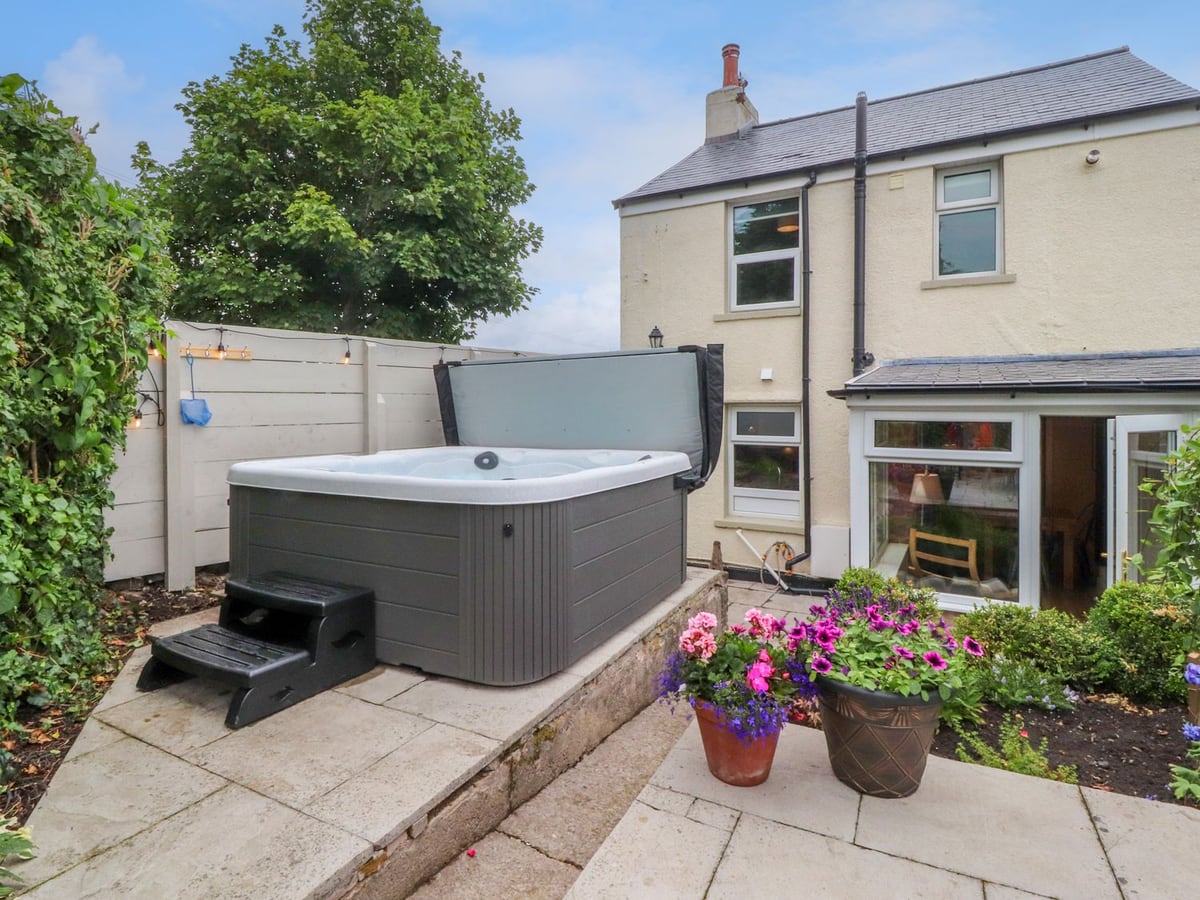 Woodman Cottage rear patio with hot tub, stone steps and flower pots beside the house