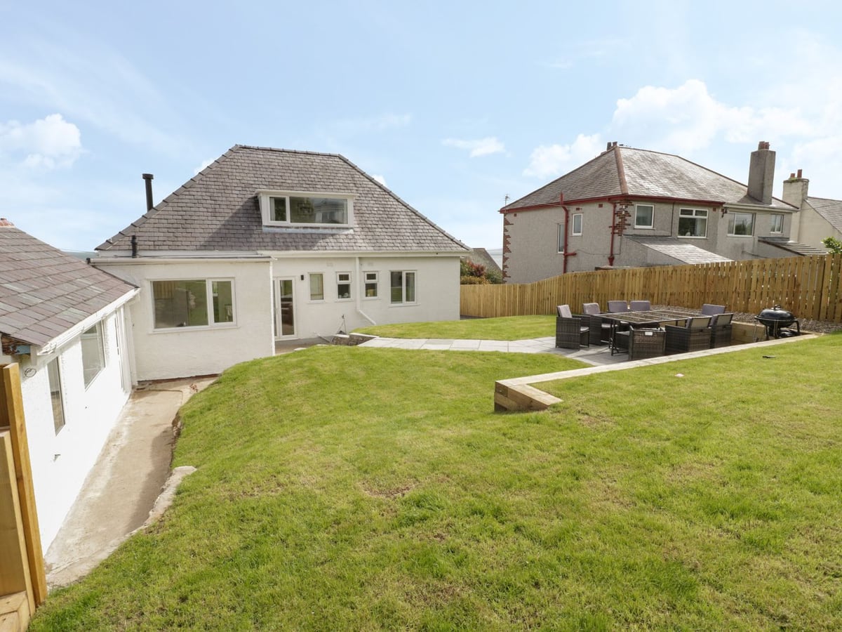 Y Gogarth rear exterior with a tiered lawn, paved paths and an outdoor dining table