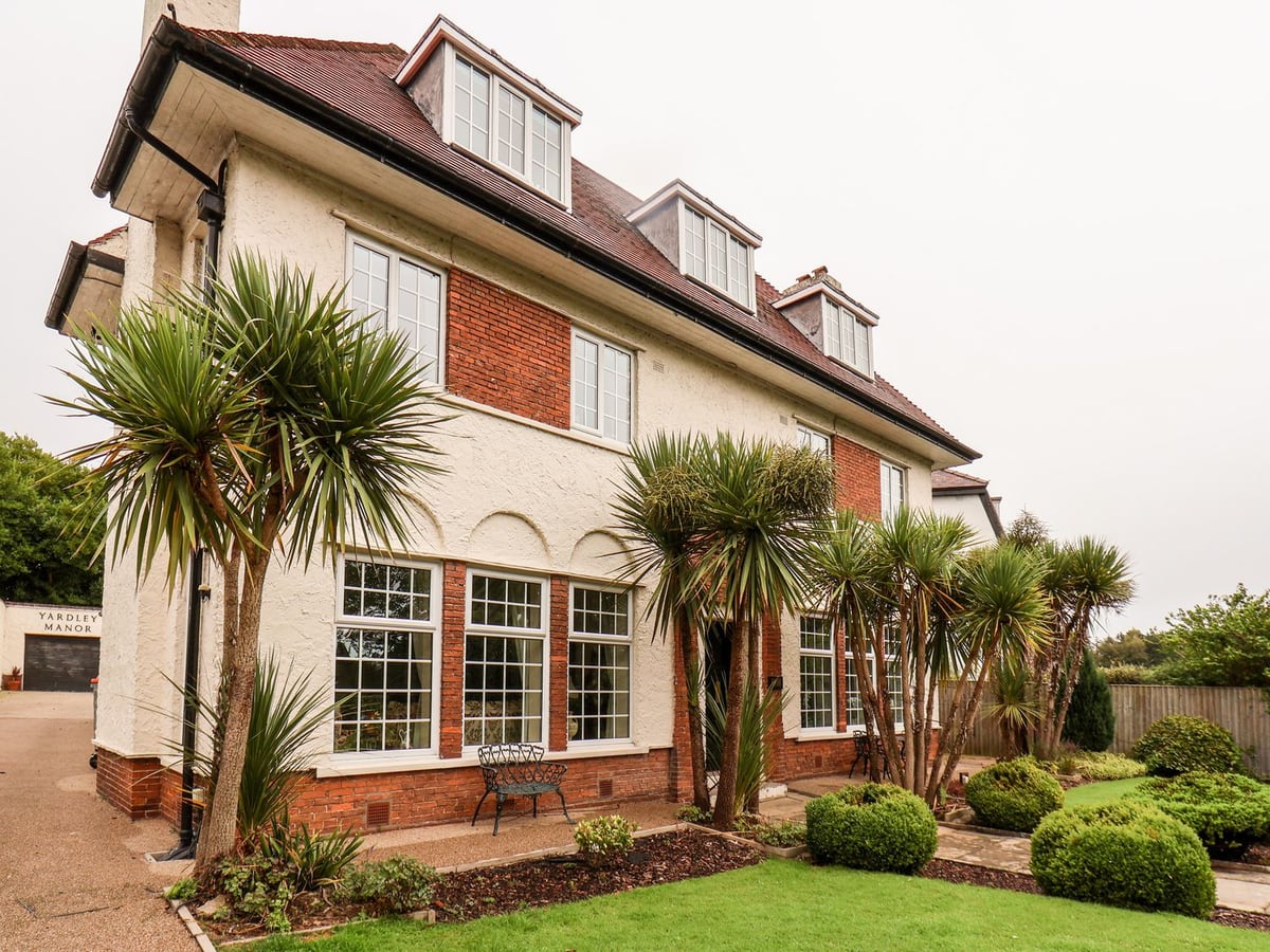 Large white house with garden, palms and red brick entrance at Yardley Manor