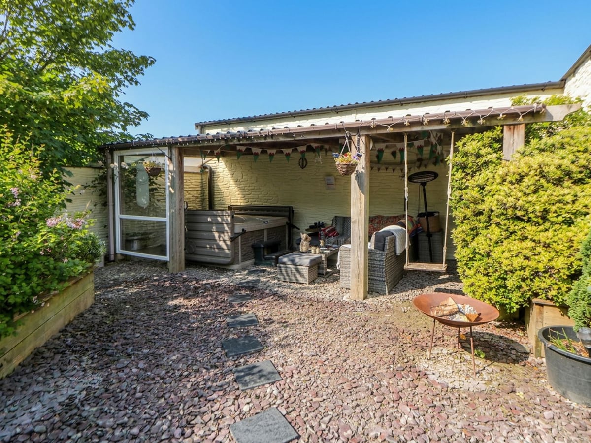 Yr Hen Llaethdy slate gravel courtyard with a covered seating area, hot tub, swing and fire bowl