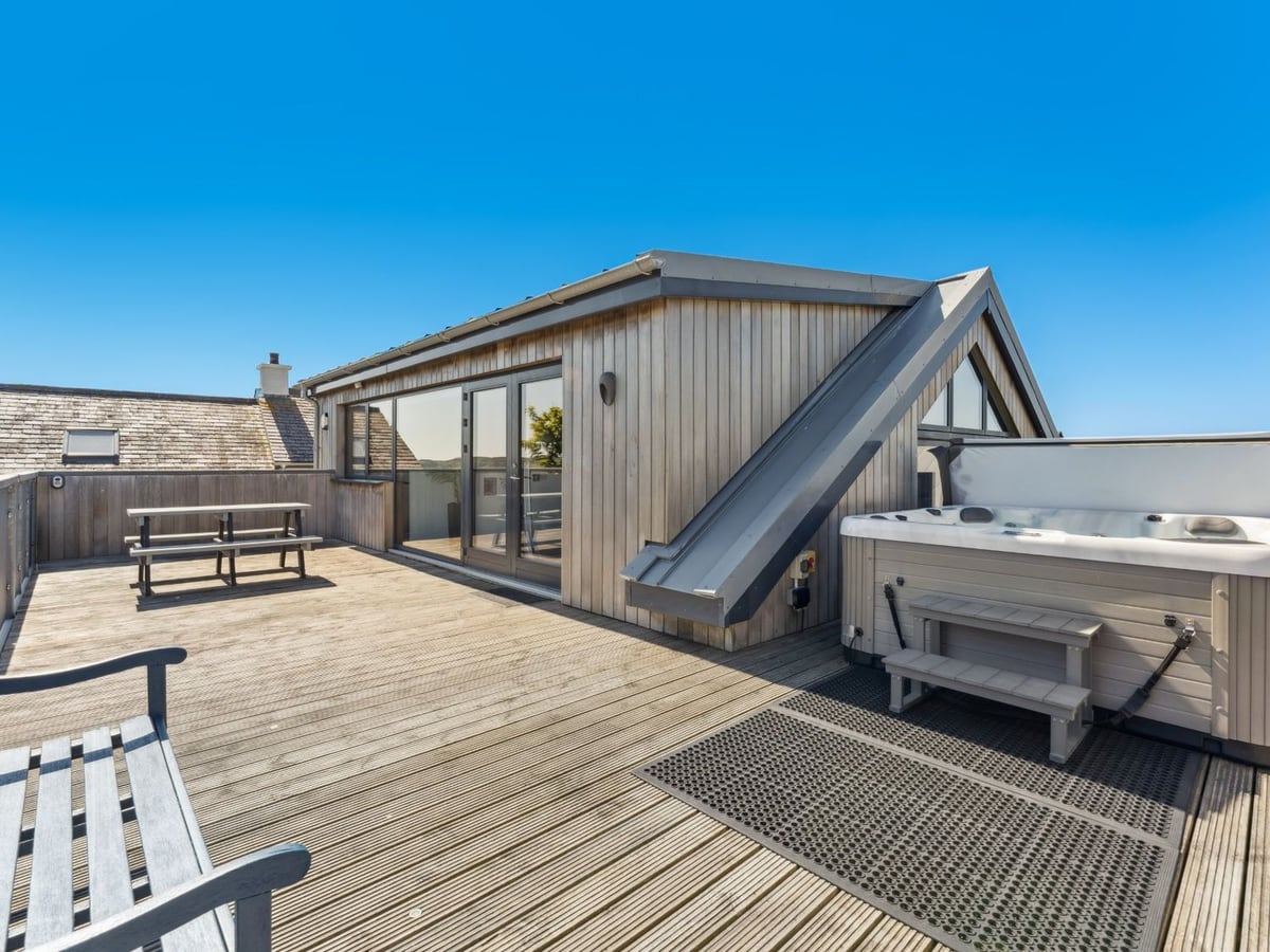 Ysbryd Y Mynydd timber-clad exterior with broad decking, a picnic table and a hot tub